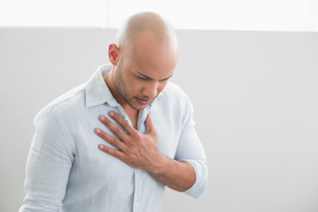 Casual young man with chest pain standing against white background