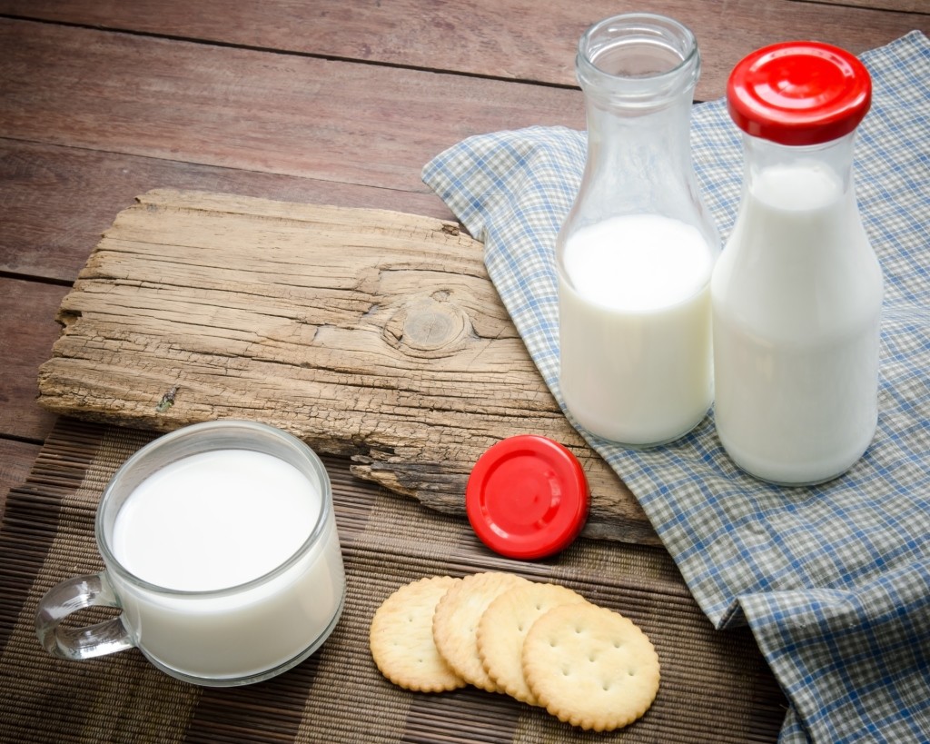 Milk bottle, milk glass and cookie put on old wood.